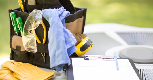Tools and checklist on a clipboard on top of an HVAC outdoor unit