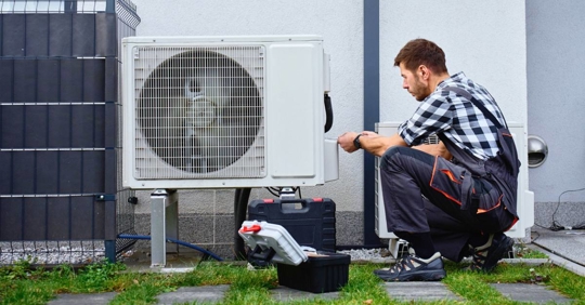 Technician servicing outdoor air source heat pump uni